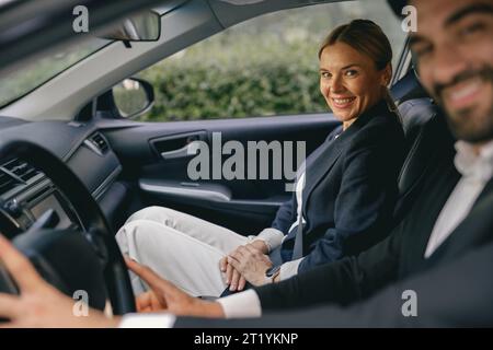 Two positive business colleagues in suit carpooling journey into work together and looks camera Stock Photo