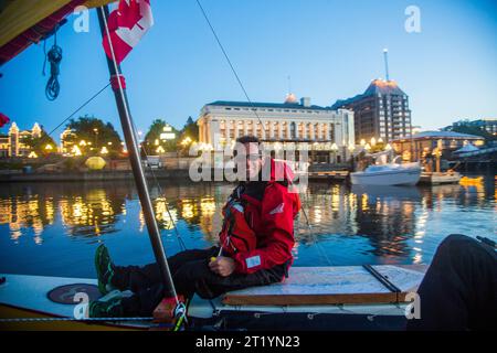 A man sits on the edie of his boat at the end of leg 1 during the Race to Alaska, a 750 mile, non-motorized boat race from Port Townsend, WA to Ketchikan, Alaska. Stock Photo