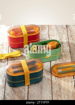 colored lunch boxes stand on a wooden table Stock Photo