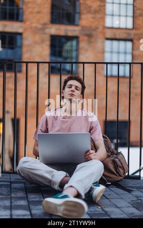 Gen Z student working on laptop after lecture on campus. Young stylish zoomer studiing outdoors. Importance of education of gen Z. Stock Photo