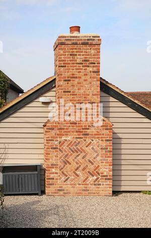 Chimney stack construction built in red flemish bond facing bricks on gable end of single storey building brickwork in zig zag panel Essex England UK Stock Photo