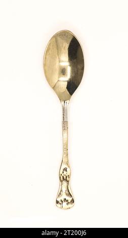 a shiny, clean and old antique bronze metal spoon used by royalty displayed for auction isolated in a white background Stock Photo