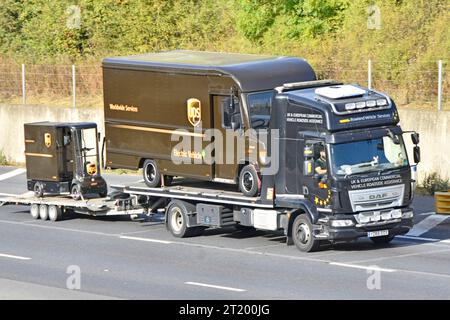 DAF flat platform recovery delivery lorry truck loaded UPS Electric parcel van towing trailer carrying miniature UPS cargo cart on M25 road England UK Stock Photo