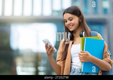 Smiling student using app on smartphone, campus Stock Photo