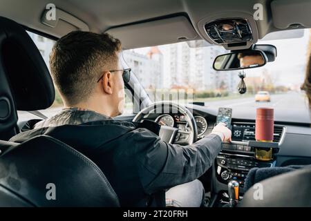A man uses a phone installed in the holder while driving Stock Photo