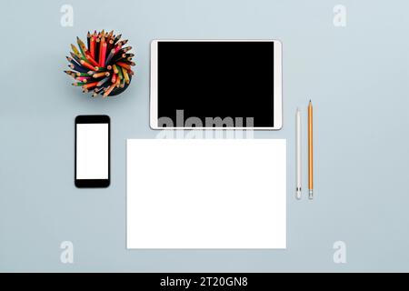 A tablet, a stylus, a simple pencil, a phone, and a blank sheet of paper on a table. A place for text and a top view. The concept of online education, Stock Photo