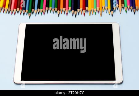 A tablet, stylus, and colored pencils lie on the table. View from the top. High quality photo. The concept of online education, training, private draw Stock Photo