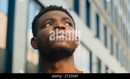 Close up pensive thinking ethnic man looking around outdoor business student guy look up on urban building think thoughtful African American male Stock Photo