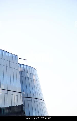 Curved and straight glass facade against a luminous white and blue sky. Ideal for representing new architectural ideas, corporate and business archite Stock Photo
