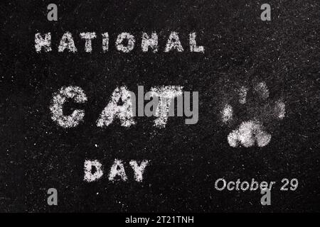 National Cat Day Poster. Holiday concept with white chalk lettering typography and footprint of cat paws isolated on black chalkboard background Stock Photo