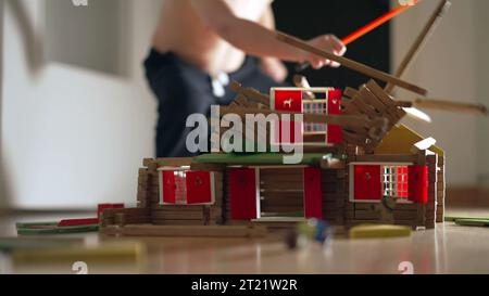 Child destroying house construction miniature. Kid kicking model wood
