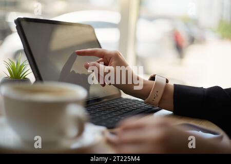 Freelance working on a tablet computer in a cafe. Female person using a modern tablet pc for distant work Stock Photo