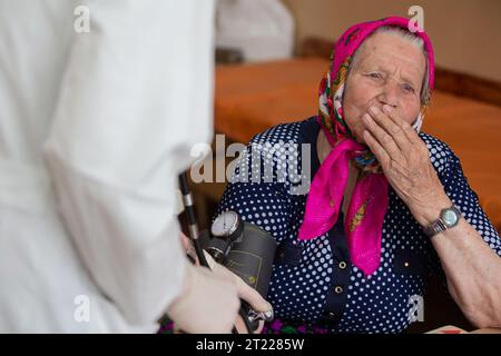 The doctor measures the pressure of an elderly woman. Stock Photo
