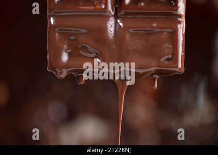 Melted chocolate drips down on a brown background. Stock Photo
