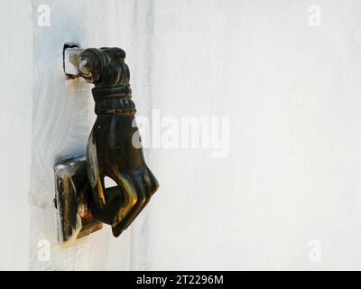 Hand shaped knocker on wooden door Stock Photo