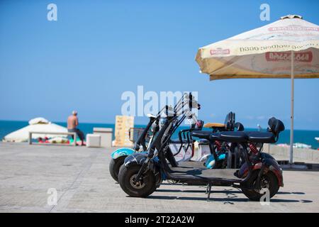 August 6, 2022. Georgia. Ureki village. Central beach with magnetic black sand. Rental electric scooters on the coastline of the beach. Stock Photo