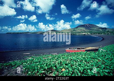 A black sand beach stretches along a coastal shoreline, formed from volcanic activity. These unique beaches are found in areas with active or dormant volcanoes, where lava flows break down into fine, dark sand grains. Stock Photo