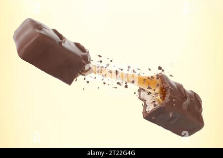 Broken chocolate bar with yummy caramel in air on beige background Stock Photo