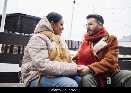 Portrait of young couple holding hands in winter outdoors and looking at each other smiling Stock Photo