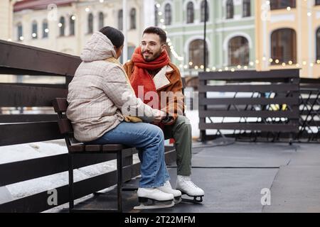 Portrait of romantic young couple holding hands in ice skating rink together, copy space Stock Photo
