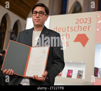 16 October 2023, Hesse, Frankfurt/Main: Austrian author Tonio Schachinger holds the certificate after being awarded the 2023 German Book Prize for his novel 'Endzeitalter. The prize for the best German-language novel of the year is awarded annually at the start of the Frankfurt Book Fair. Photo: Arne Dedert/dpa Stock Photo