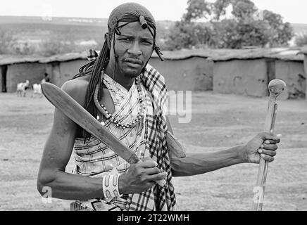 Tribal man of Maasai Mara carrying a short sword, a stick and a club entertaining the visitors with his traditional customs in his village Stock Photo