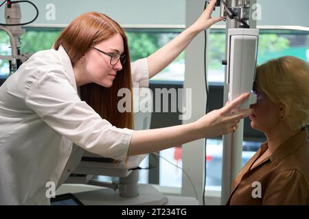 Red-haired doctor uses a dioptrimeter in her work Stock Photo