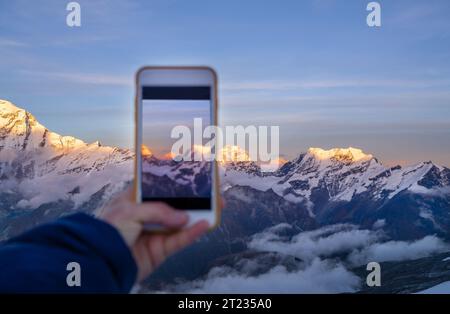 Young woman taking a vertical photo the third world's highest mountain Kangchenjunga 8586m during sunset time from the Mera Peak high camp. Climbing e Stock Photo