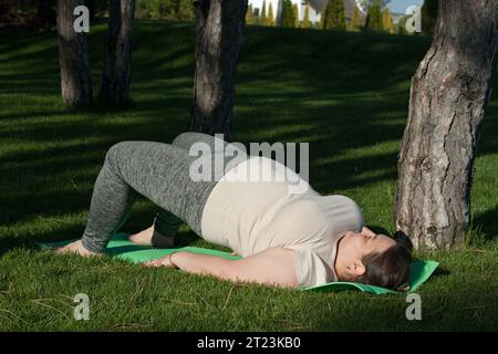 Fitness, outdoor training, weight loss. Fat woman doing exercises in nature. overweight middle-aged woman does Pilates in city park. Healthy lifestyle Stock Photo