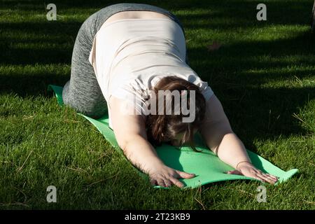 Fitness, outdoor training, weight loss. Fat woman doing exercises in nature. overweight middle-aged woman does Pilates in city park. Healthy lifestyle Stock Photo