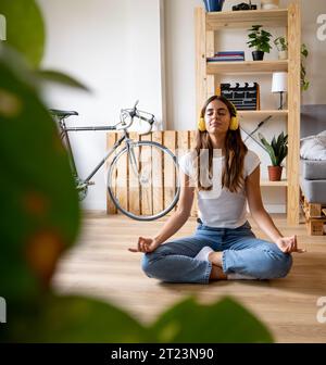 Young woman practicing yoga and meditating in modern apartment Stock Photo