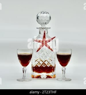 Studio shot of a Christmas decanter of port wine and a starfish decoration with two cut glass crystal tumblers on a white background Stock Photo