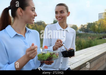 Business people eating from lunch boxes outdoors Stock Photo