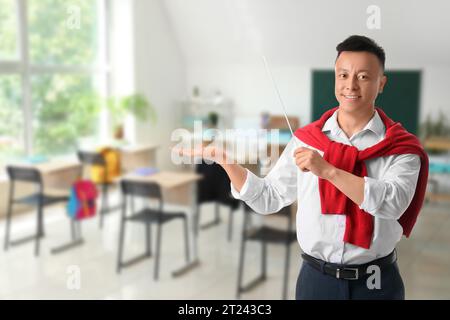 Portrait of male Asian teacher with pointer in classroom Stock Photo