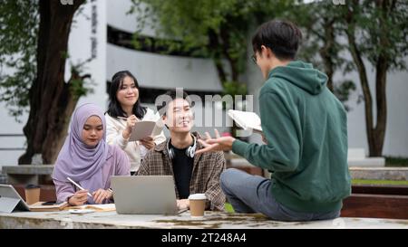 A smart and cheerful young Asian male college student in a green hoodie is helping his friends with math, tutoring and preparing for the exam in a cam Stock Photo