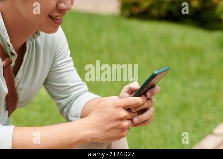 Cropped image of smiling young man texting friend or girlfriend Stock Photo