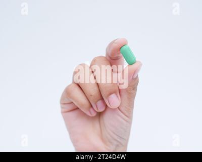 Hand holding green medical pills on white background Stock Photo