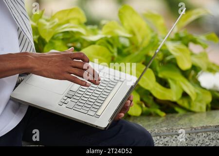 Closeup image of Black man working on laptop, coding and sending e-mails Stock Photo
