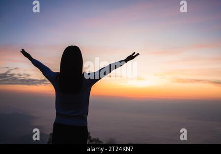 Silhouette of woman hand praying spirituality and religion, Woman raising his hands in worship. Christian Religion concept background. Stock Photo
