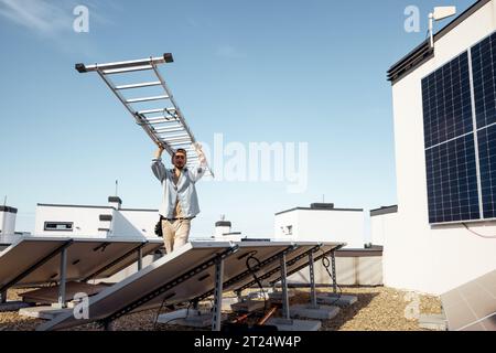 Man carries ladder during solar panels installation Stock Photo