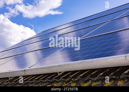 Solar panels of a photovoltaic system on a private residence with contaminated roof tiles on the roof of the house against clouds Stock Photo