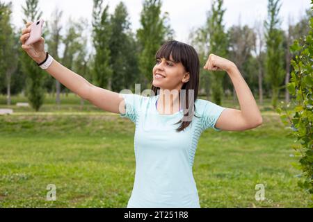 Smiling sport woman fitness training outdoors taking a selfie with smartphone. Strong young runner athlete workout. Stock Photo