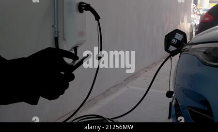 EV charging station for electric car with mobile app display charger status . The electric power is produced from sustainable resources to supply to Stock Photo