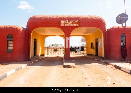 A man in traditional Masai clothes standing at the entrance gates of Amboseli National Park in Kenya Stock Photo