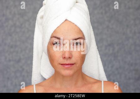 Portrait of caucasian middle aged woman of 40s with towel on head looking at camera Stock Photo