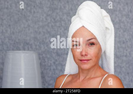Portrait of caucasian middle aged woman of 40s with towel on head looking at camera Stock Photo