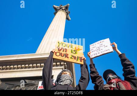 London, UK. 14 Oct 2023: Two masked female pro-Palestinian protesters hold placards in Trafalgar Square, London, UK at a demonstration against Israeli Stock Photo