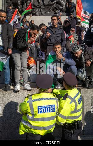 London, UK. 14 Oct 2023: Two Metropolitan Police officers speak with pro-Palestinian protesters on the base of Nelson's Column in Trafalgar Square, Lo Stock Photo