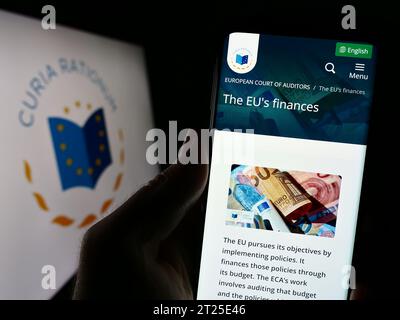 Person holding smartphone with webpage of EU institution European Court of Auditors (ECA) in front of logo. Focus on center of phone display. Stock Photo