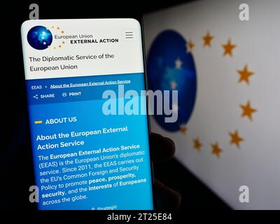 Person holding cellphone with webpage of EU institution European External Action Service (EEAS) with logo. Focus on center of phone display. Stock Photo